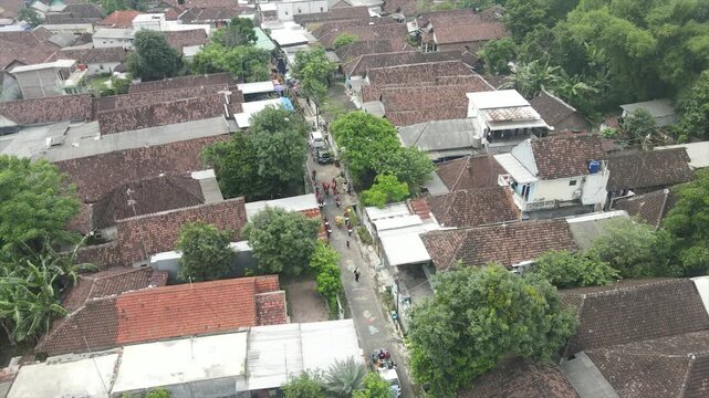 Aerial 4K view of a densely populated rural village surrounded by lush green trees in Indonesia