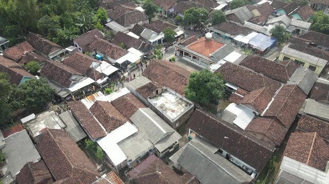 Aerial 4K view of a densely populated rural village surrounded by lush green trees in Indonesia