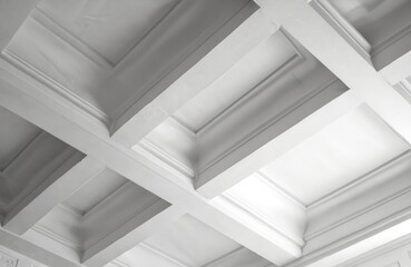 Obraz premium White coffered ceiling with recessed panels shows dimensional pattern and shadow play. Intricate architectural detail creates elegant interior design texture.
