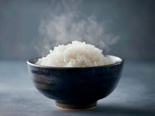 湯気が立ち昇る炊きたてのご飯が盛り付けられた和食器の茶碗と和食のイメージ