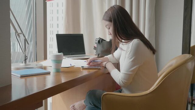 A serene workspace featuring a young individual focused on their tasks, bathed in natural light. The arrangement includes a coffee cup, notebooks, and a laptop, promoting a productive and inviting atm