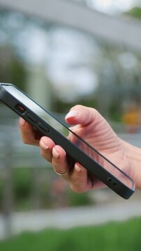 Close-up side view of a woman s hand interacting with a smartphone outdoors, tapping and scrolling on the screen, representing digital communication and modern mobile technology in everyday life. Slow