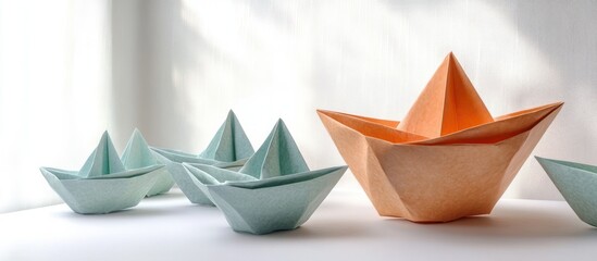 group of pastel teal origami paper boats with one larger orange paper boat on a white surface in soft window light, calm and hopeful mood