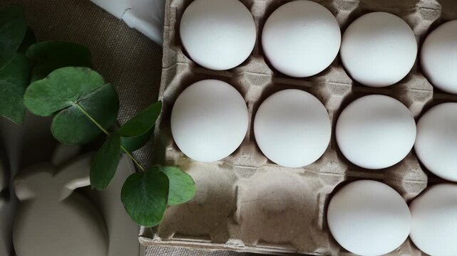 There are rabbit-shaped molds and several white eggs in a cardboard box on the table.