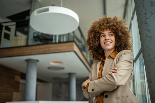 Businesswoman with afro hair confidently smiling in modern office