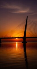 Obraz premium Sunset over water with bridge silhouette.