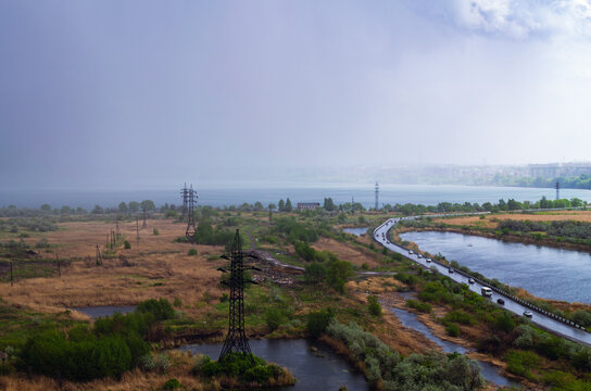 Rainstorm over lake and industrial cityscape