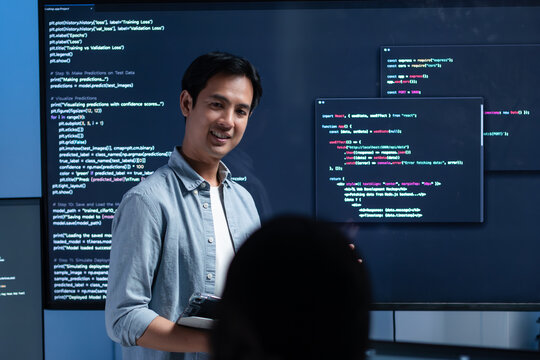 Male software engineer presenting a Coding Task, AI chatbot workflow with code on multiple monitors in a modern office. coding collaboration and agile projects Concept.