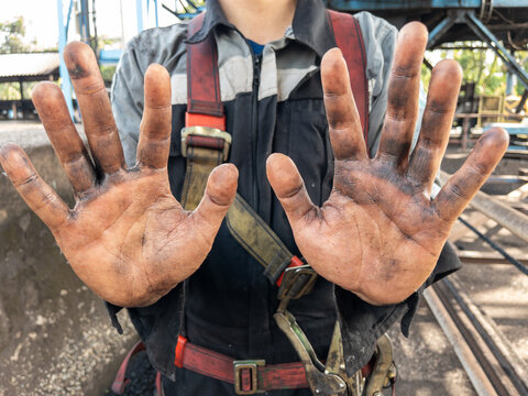 Asian man showing his hands dirty from coal.Dirty hands of a hardworking employee in overalls. Manual jobs concept.