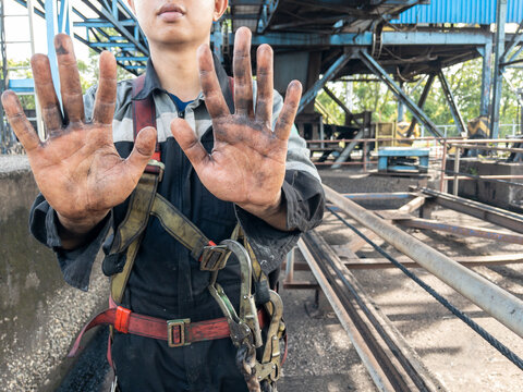 Asian man showing his hands dirty from coal.Dirty hands of a hardworking employee in overalls. Manual jobs concept.
