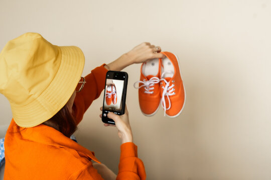 Woman creating authentic user generated product photo of bright sneakers for online marketplace emphasizing real life visual storytelling trust based marketing and organic digital sales