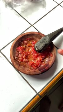 Sambal bawang in the making using traditional tool called ulekan. Sambal bawang is a delicious traditional sauce from Indonesia made from chilies and garlic.
