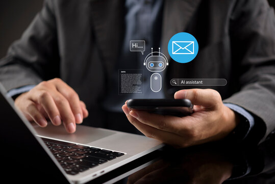 Businessman using laptop and smartphone with virtual AI assistant and email hologram. Concept of artificial intelligence for automated chat, smart business communication, digital marketing support.