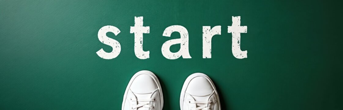 White sneakers stand on green surface before word start written in white chalk. Symbolizes new beginnings, launching ventures, and forward movement.