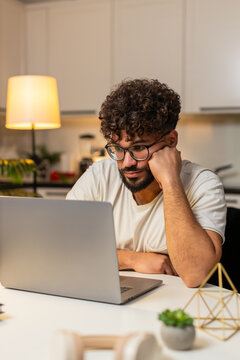 Arabian man at home ends remote laptop job feels bored tired stress burnout wants rest. Egyptian guy sitting at table rubs face sighs low energy looks aside plans pause from tasks tonight.