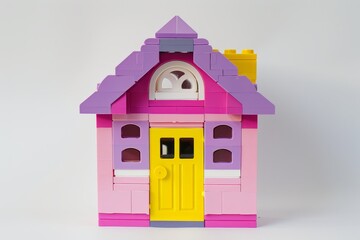 Fototapeta premium Simple pink and purple LEGO house with yellow door on white background, professional photography with space for text