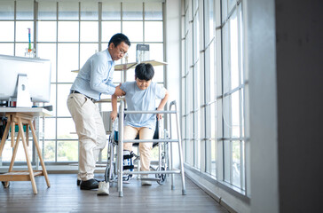 Fototapeta premium Father assisting young boy during physical therapy session using a walker in hospital