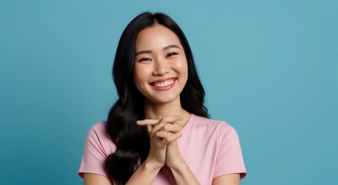 Young Asian Woman Expressing Surprise and Joy With Wide Eyes and Big Smile, Holding Hands to Cheeks