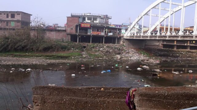 Closeup  video showing garbage pollution near river bank under the bridge of ratti road in mandi, himachal pradesh, india during winter daytime.