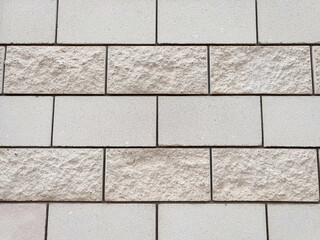 Obraz premium Modern beige brick wall texture with smooth and rough rectangular blocks in rows