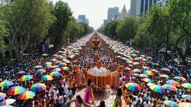 Large crowd with colorful umbrellas and dancers in a city parade