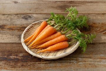 新鮮な葉付きにんじん(木目背景)