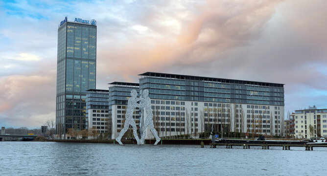 Berlin, Germany - December 28, 2017: The Molecule Man sculpture by Jonathan Borofsky stands in the Spree river in front of the Allianz Treptowers office complex during sunset in Berlin, Germany.
