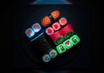 A plate of sushi with various pieces and colors on a black background