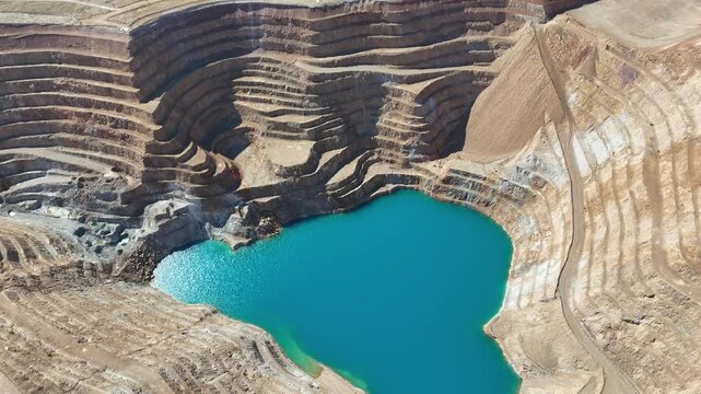 Aerial View of Open Pit Gold Mine with Terraced Excavation and Blue Lake