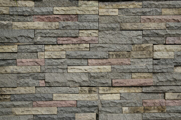 Fototapeta premium 3d cladding stone wall background with grey, reddish pink and beige tones, split stones pattern made from stacked slabs of natural rocks, panel for exterior decoration