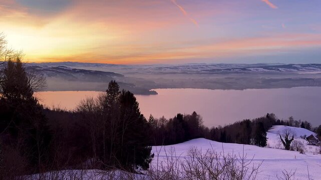 Intense winter sunset on Zugerberg overlooking Lake Zug, snow-covered landscape glowing under a dramatic red and golden evening sky.