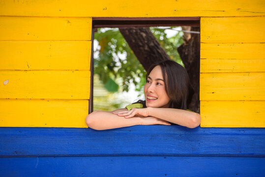 Smiling woman leaning on colorful wooden window outdoors