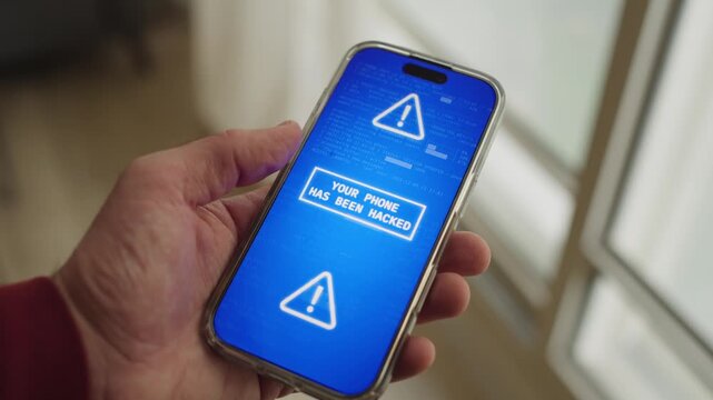 Person holding smart phone as message appear warning of hack attack on device. Phone is blocked and hacked by malware or remote access of cyber security breach. Personal data is lost and access denied