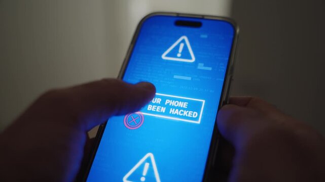 Close up on mobile phone message appearing on screen as device is hacked. Man holding smartphone when glitch and notification pop up alerting phone is taken over by hacker group or malware virus app