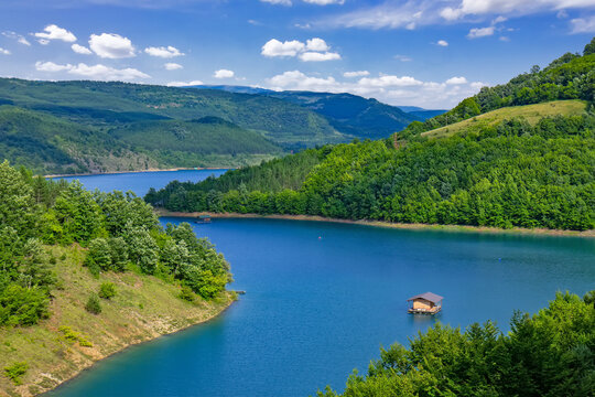 Panoramic landscape of Lake Zavoj surrounded by forested hills and mountains near Pirot in southeastern Serbia under blue sky