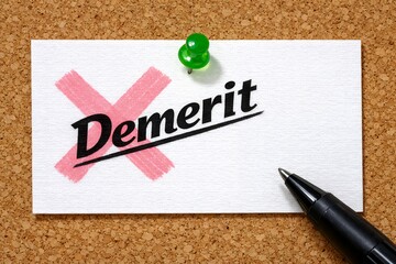 コルクボードにピン留めされたメモ用紙に書かれたデメリットの文字と赤いバツ印とペン