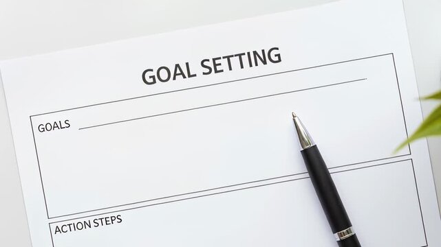 goal setting sheet with pen on desk accompanied by green plant in bright minimal workspace