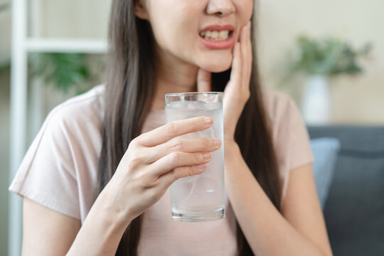 Face expression suffering from sensitive teeth, Asian young woman touching cheek