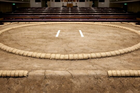 日本の伝統格闘技である相撲が行われる土俵と誰もいない静かな観客席の風景写真