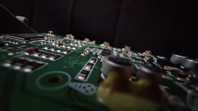 Macro steady shot of a high-quality electronic circuit board focusing on a copper wire inductor coil and electrolytic capacitors on a green PCB.