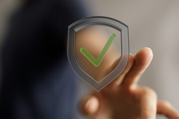 Concept of approval, security, and protection shown with hand touching a shield icon with a green checkmark. Perfect for