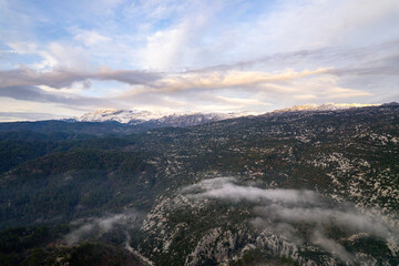 A stunning drone perspective of &Ccedil;altepe village on the St Paul Trail, showcasing the harmony between traditional rural life, green agricultural fields, and the dense pine forests covering the rugged s