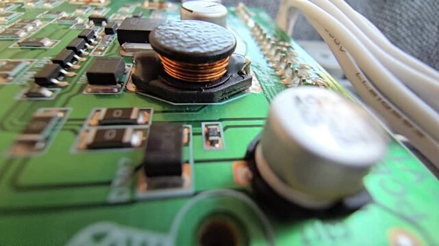 Macro of STM32 microchip on green PCB. Close-up of soldered white wires, electrolytic capacitors, inductors, and SMT components. High-tech circuit board for industrial hardware and engineering.