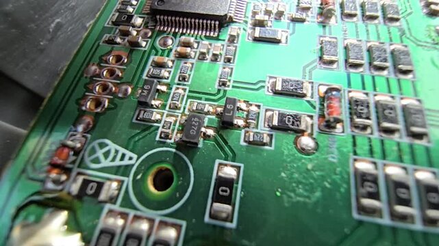 Macro of STM32 microchip on green PCB. Close-up of soldered white wires, electrolytic capacitors, inductors, and SMT components. High-tech circuit board for industrial hardware and engineering.