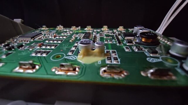 Macro of STM32 microchip on green PCB. Close-up of soldered white wires, electrolytic capacitors, inductors, and SMT components. High-tech circuit board for industrial hardware and engineering.