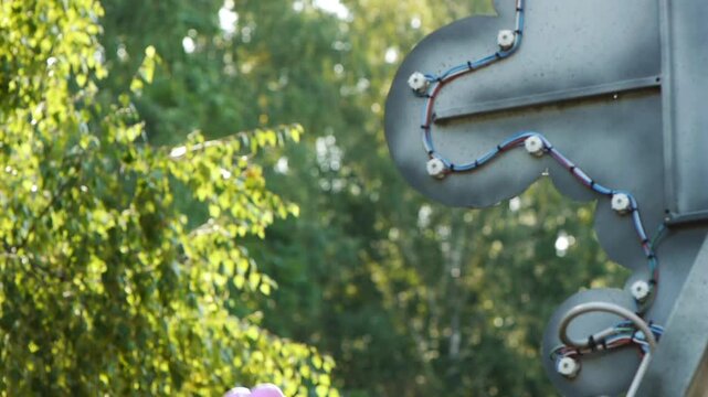 Little beautiful girl rides on swing in summer city park.