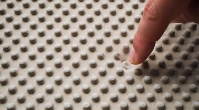 Individual finger touch on a soft pliable textured surface featuring a regular array of rounded protrusions