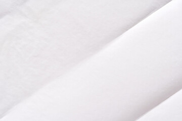 Minimalist close-up of soft white fabric texture with folded layers for background or textile...