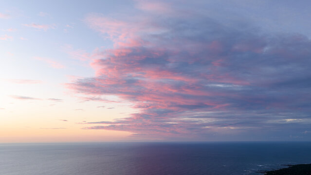 Pink and purple clouds paint the sky above the vast Pacific Ocean near Avellanas Beach, Costa Rica, during twilight