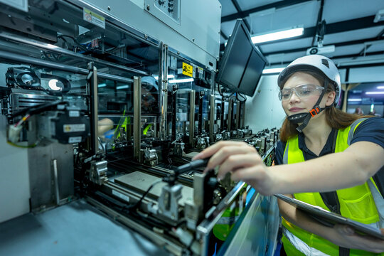 A robotics engineer uses a tablet to program a robot with a machine vision system, while her colleague calibrates the end-of-arm tooling on another unit in a system integration lab.
